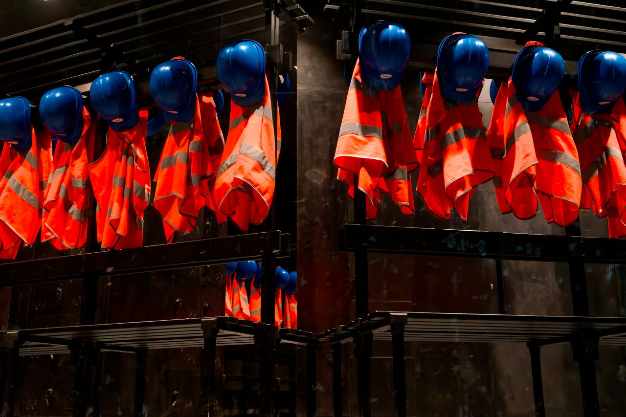 about-01 Row of orange safety vests and blue helmets hanging in industrial setting