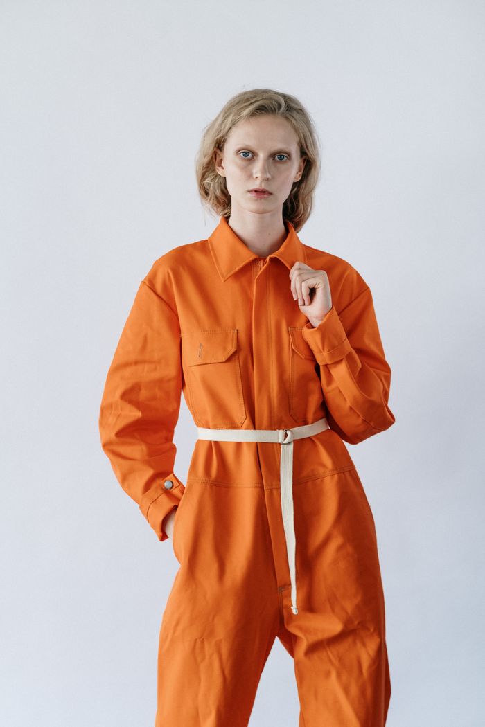 services-02 Stylish woman posing in orange utility jumpsuit against a plain background.